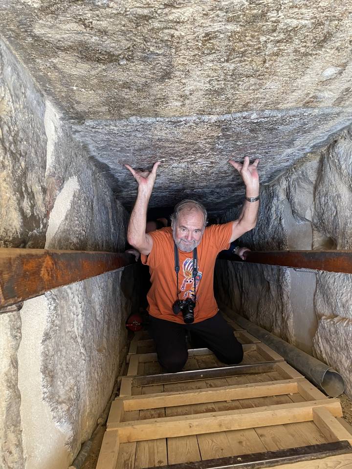 Person navigating a narrow tunnel in a historical site.