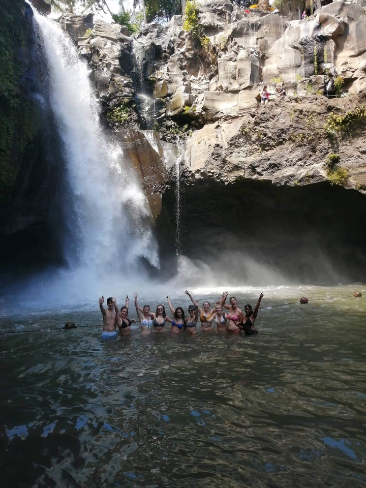 Group of people enjoying a waterfall swim.