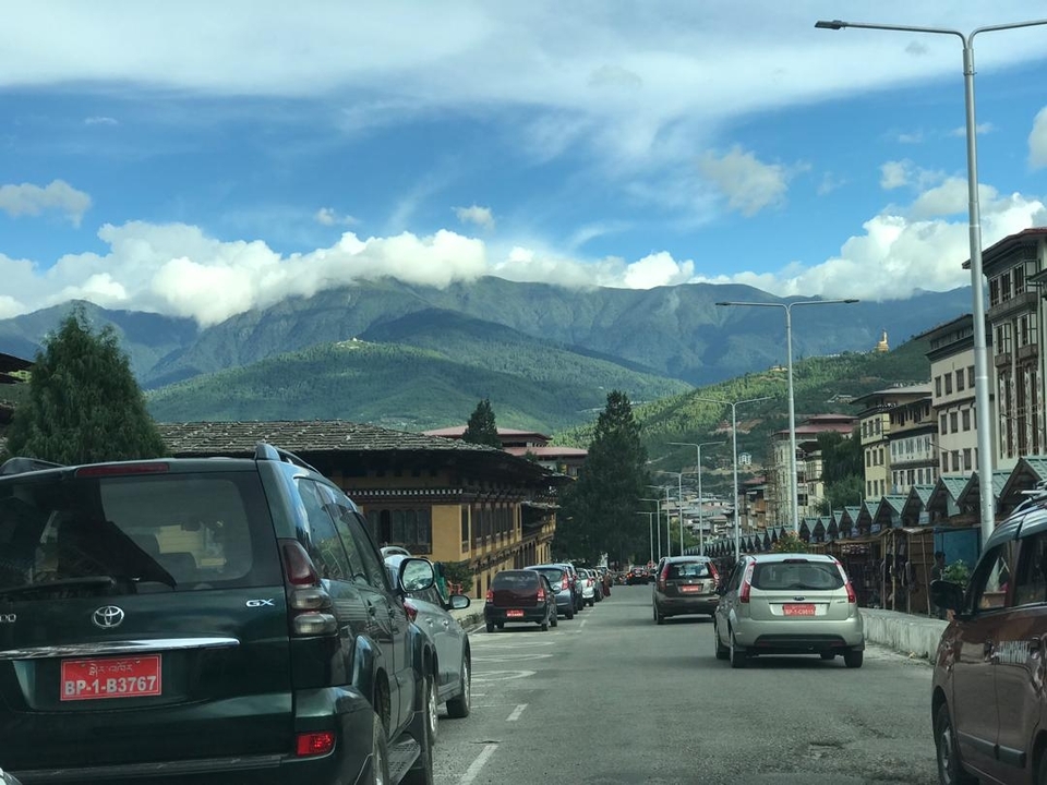 Street view with parked cars and mountains in the background.