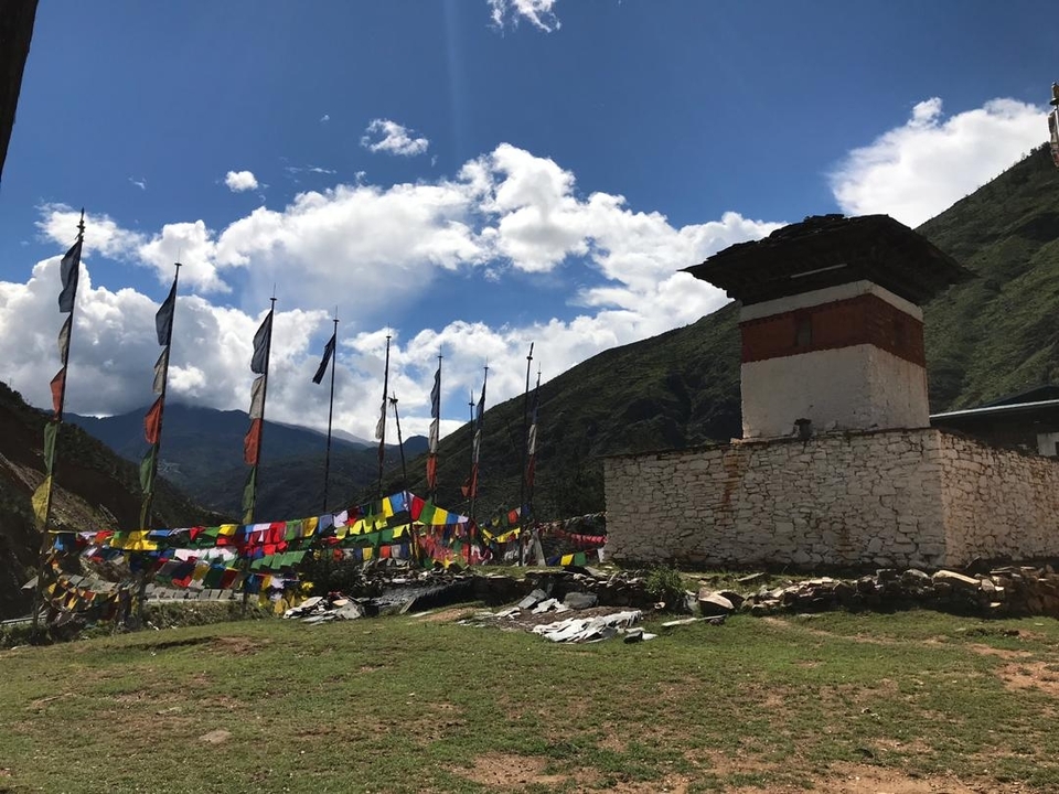 Chorten with colorful prayer flags and mountains.