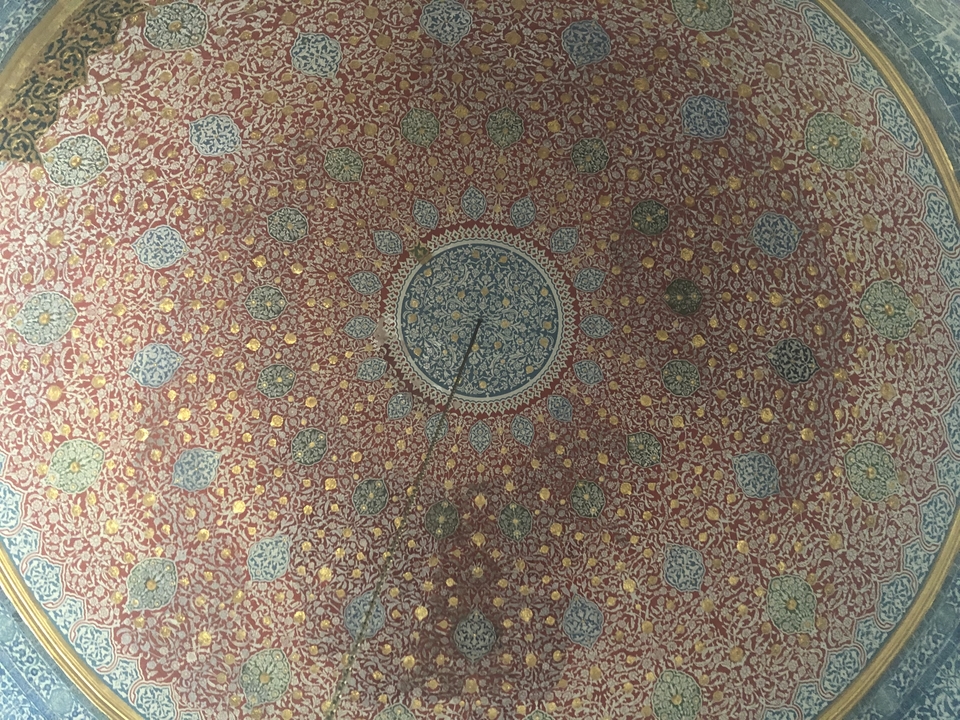 Plafond décoratif complexe avec motif circulaire.