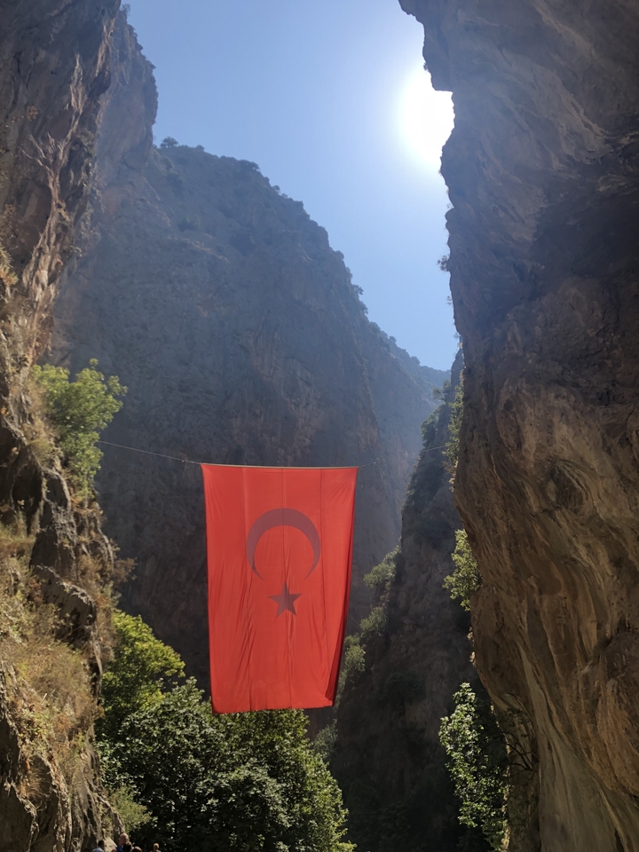 Canyon avec un grand drapeau turc rouge suspendu entre les falaises.