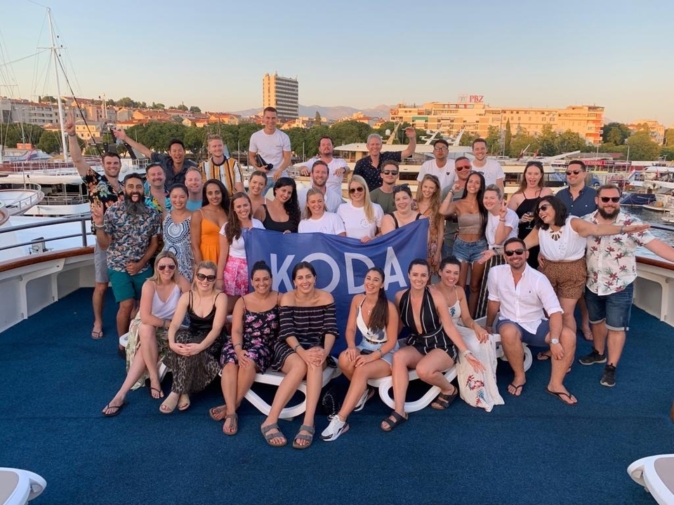 Grand groupe posant sur un bateau avec un paysage urbain en arrière-plan.