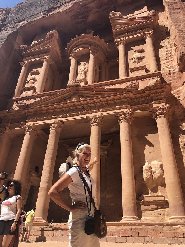 Person standing in front of Petra's historic facade.
