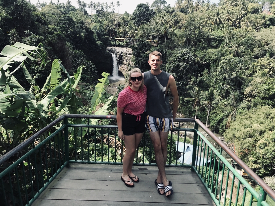 Couple posing in front of scenic waterfall landscape.