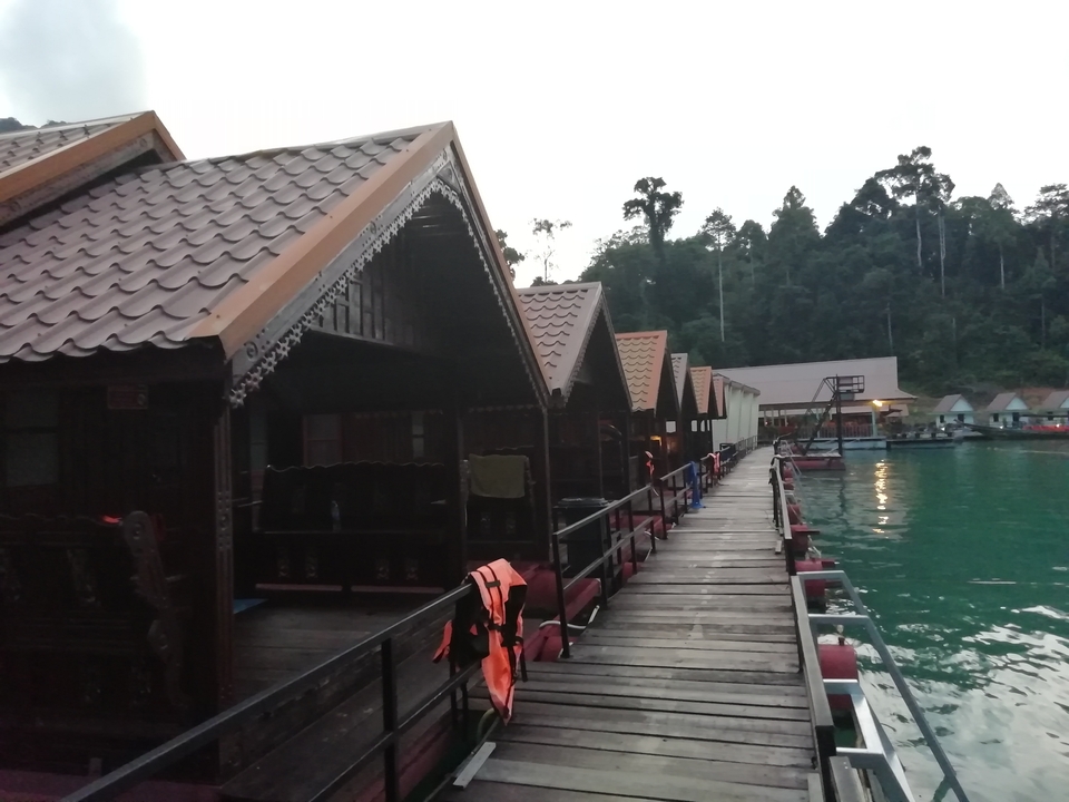 Floating cottages on a lake with tree-covered hills.