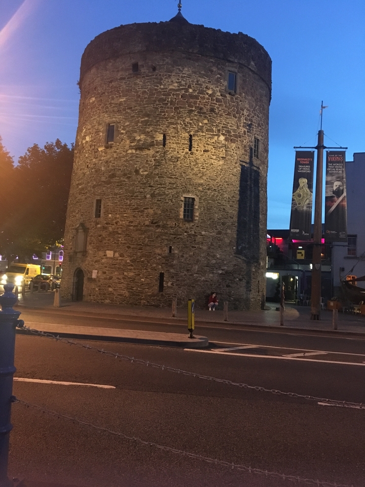 Grande tour de pierre ronde avec des bannières dans un environnement urbain.