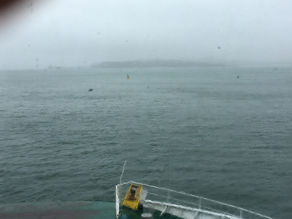 Vue d'eau avec terre lointaine dans des conditions brumeuses.