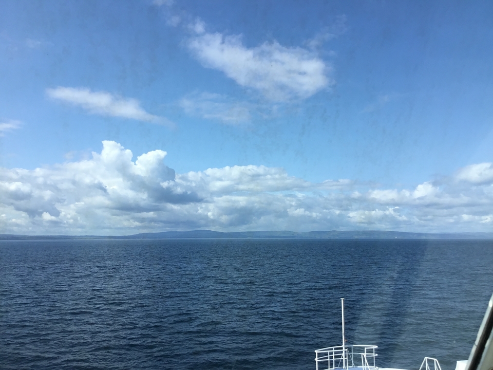 Vue de l'océan avec des terres lointaines sous un ciel nuageux.