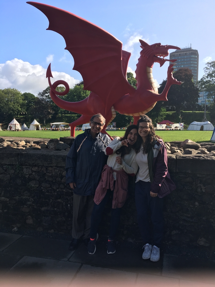 Trois personnes debout devant une grande sculpture de dragon rouge.