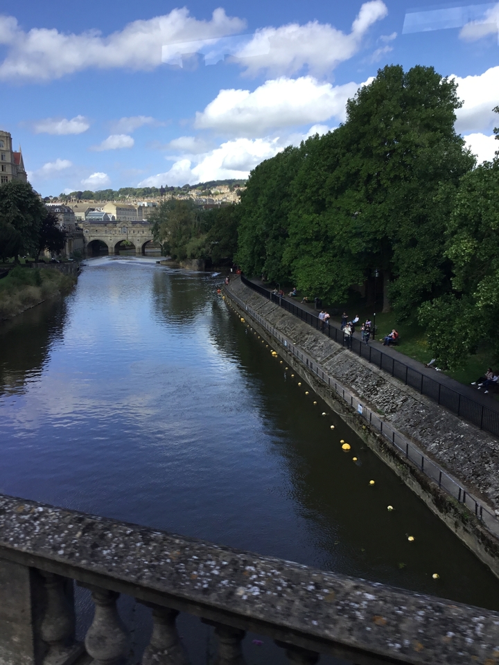 Rivière avec pont, entourée de verdure et de bâtiments.