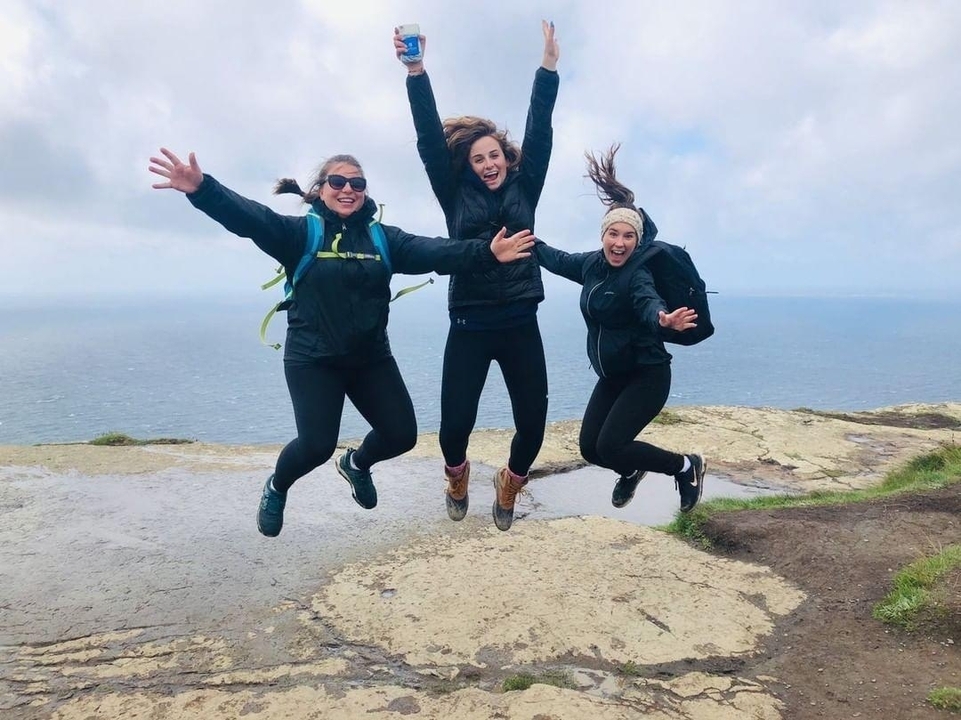 Three women jumping with Cliffs of Moher background