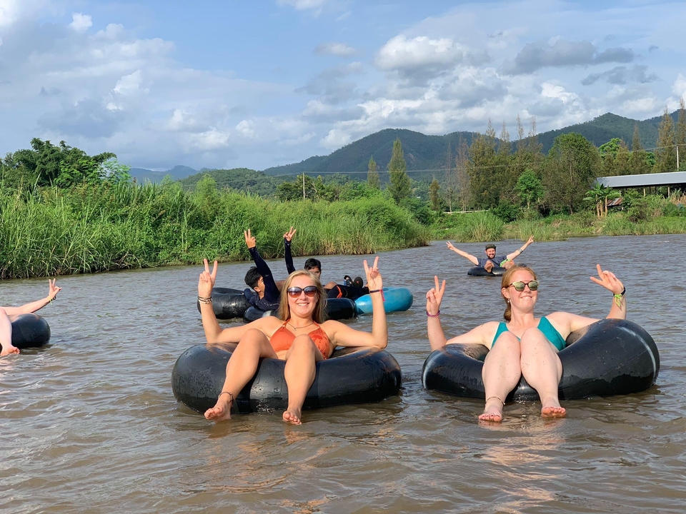 People enjoying tubing in a river with a scenic mountain view.