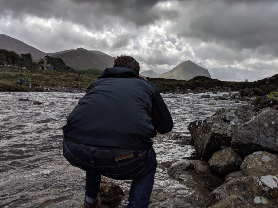 Person photographing a river in a mountainous area.