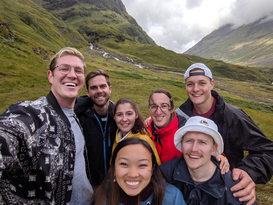 Group selfie with a scenic hilly backdrop.