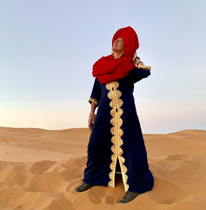 Personne debout dans un désert avec une tenue traditionnelle.