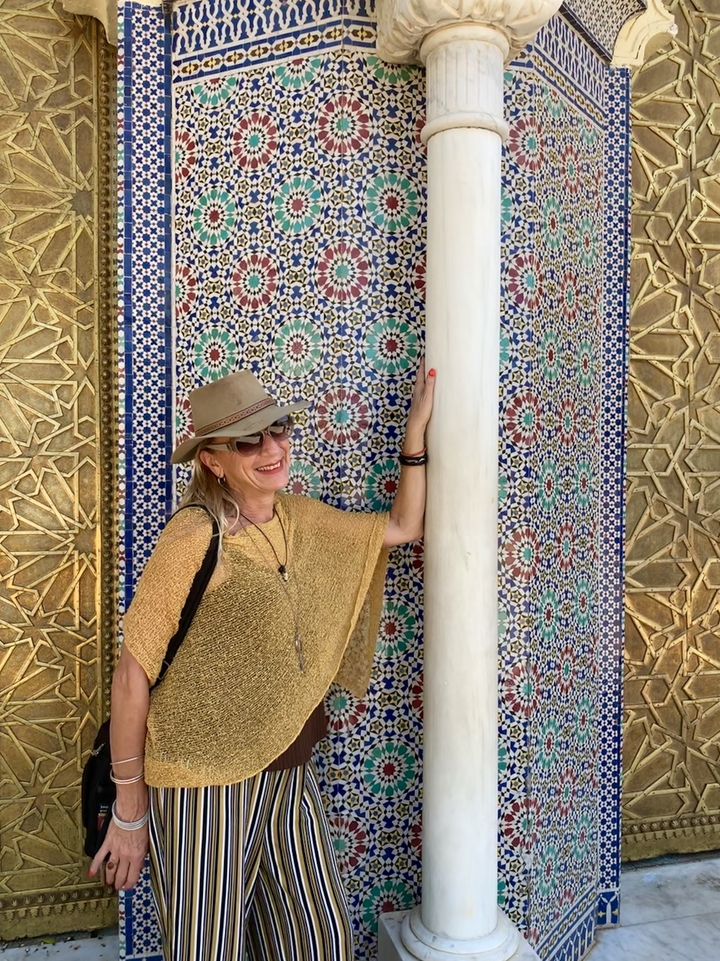 Une femme pose à côté d'un mur décoratif en mosaïque.