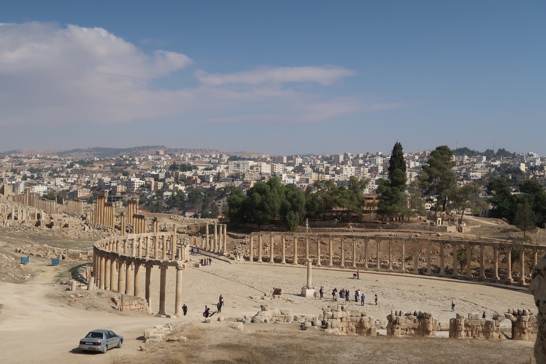Vue panoramique de ruines romaines antiques avec une ville en arrière-plan.
