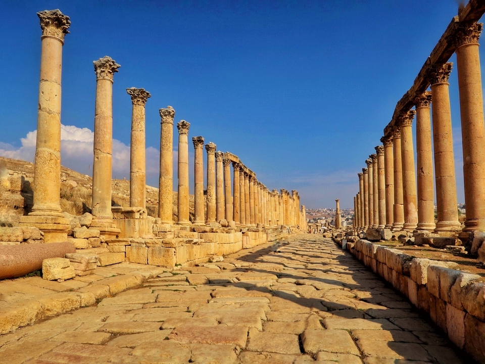 Une vue en perspective d'anciennes colonnes bordant une voie romaine.