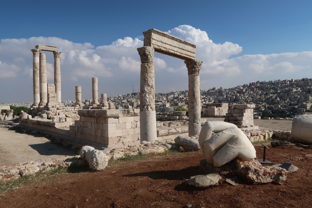 Ruines avec colonnes et toile de fond urbaine sous un ciel bleu.