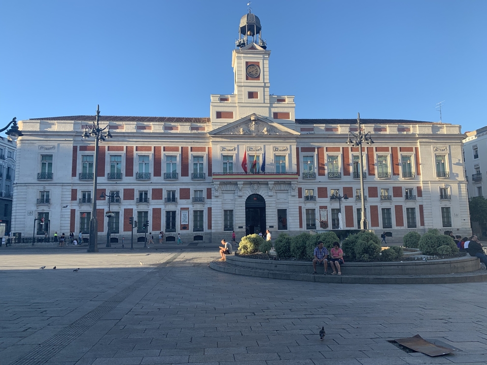 Large government building with flags and a clear blue sky.