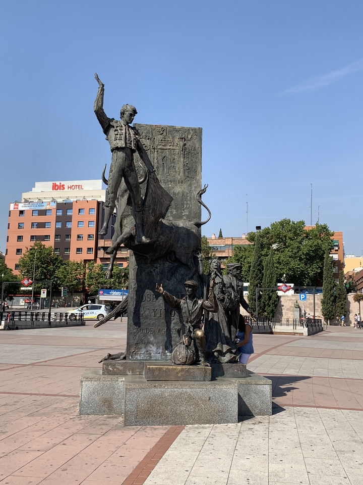 Statue of a bullfighter with people and buildings in the background.