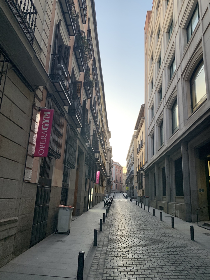 Narrow city street with multiple tall buildings and signs.