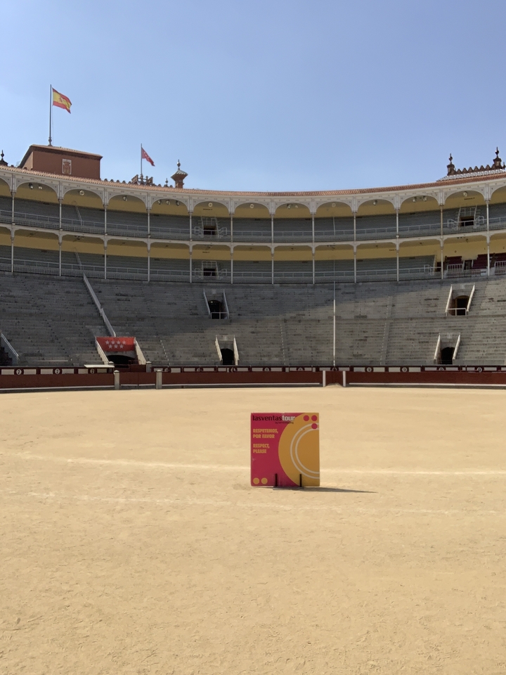 Bullring with informational sign in the center, surrounded by seating areas.