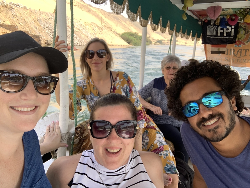 Groupe de personnes profitant d'une promenade en bateau avec des sourires et des lunettes de soleil.
