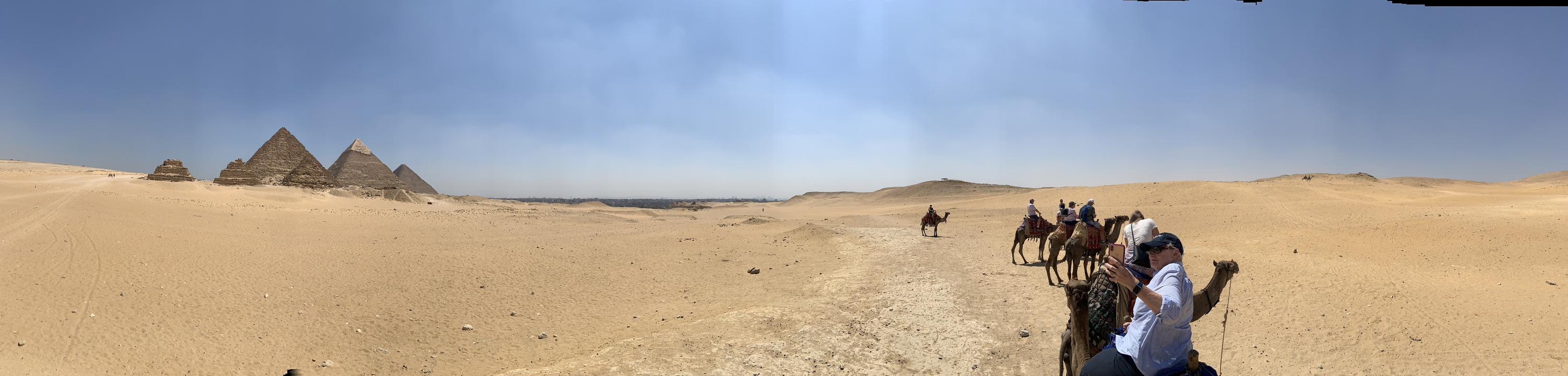 Chameaux dans un paysage désertique avec des gens qui montent sous un ciel bleu.