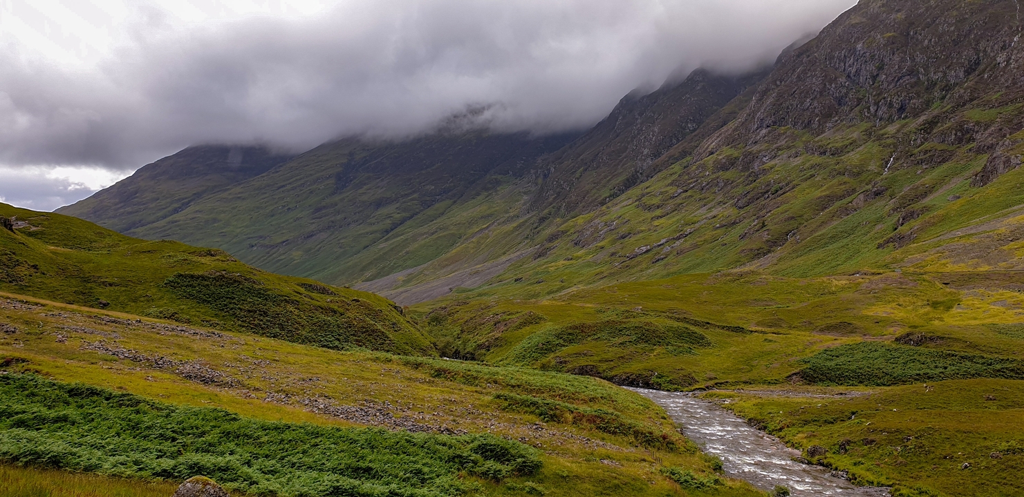 A dramatic landscape with low clouds covering the mountains.