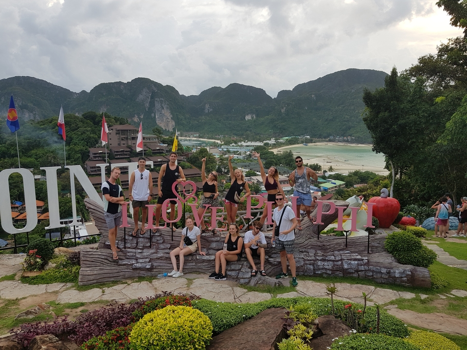 Group of tourists with signs at a scenic viewpoint.