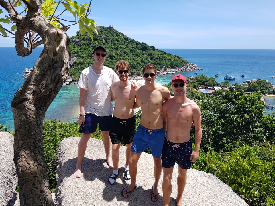 Group of friends with a scenic ocean view from a hill.