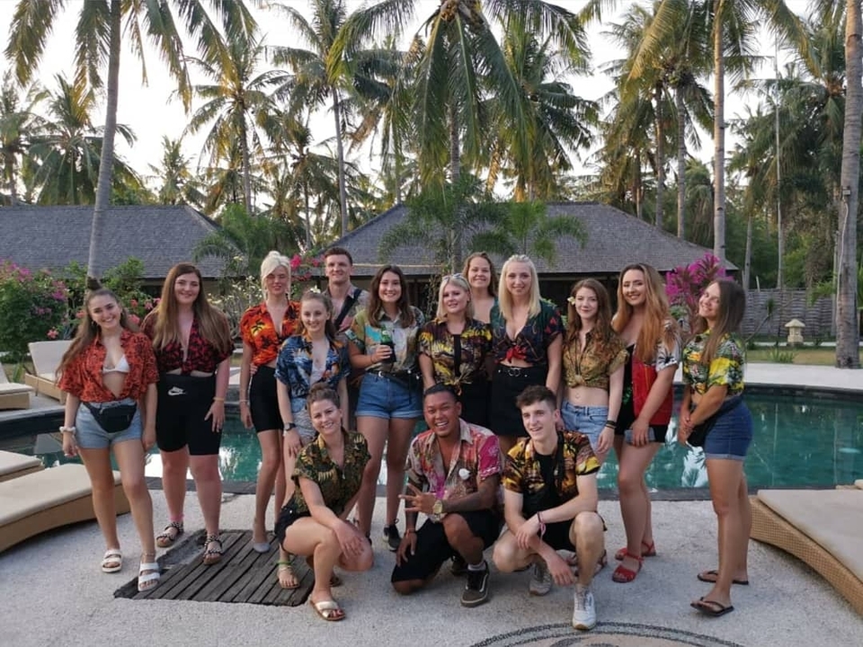 Group of people posing in colorful shirts near a pool