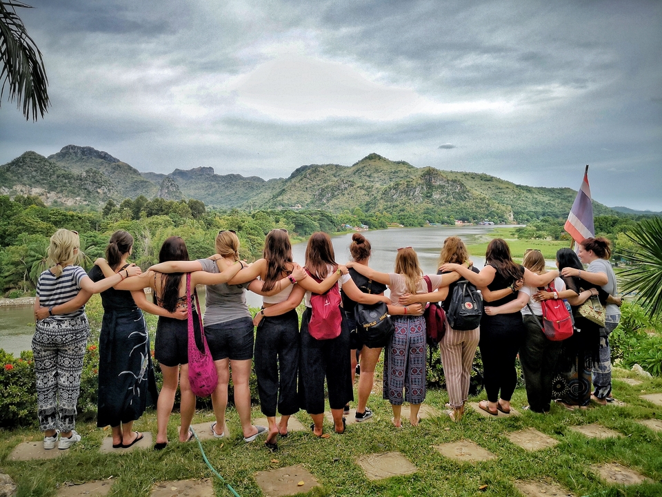 Group standing arm-in-arm overlooking a scenic landscape