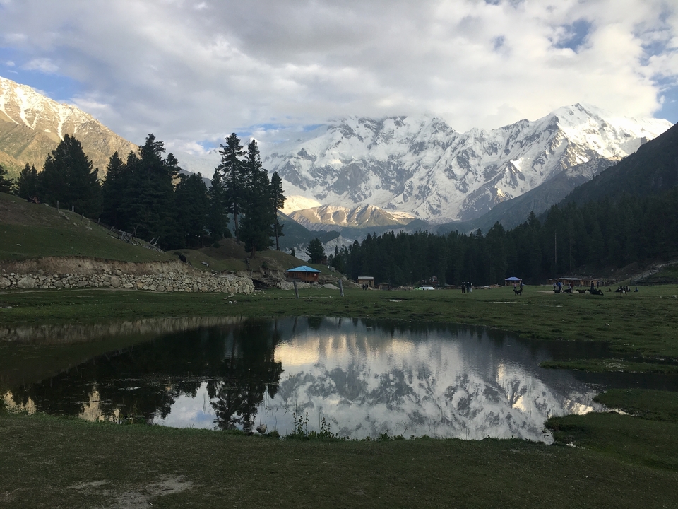 A mountainous landscape with a pond reflecting the surroundings.