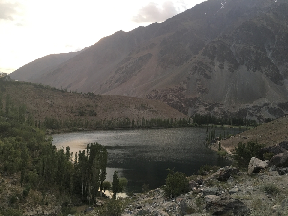 A peaceful mountain lake with trees and hills surrounding it.