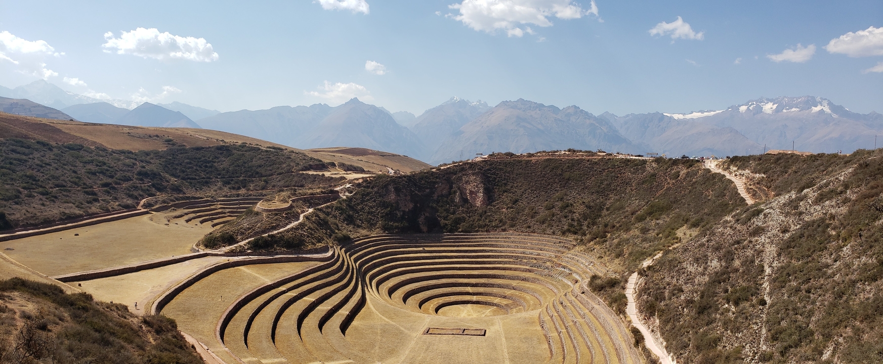 Paysage agricole en terrasses sur fond de montagnes lointaines.