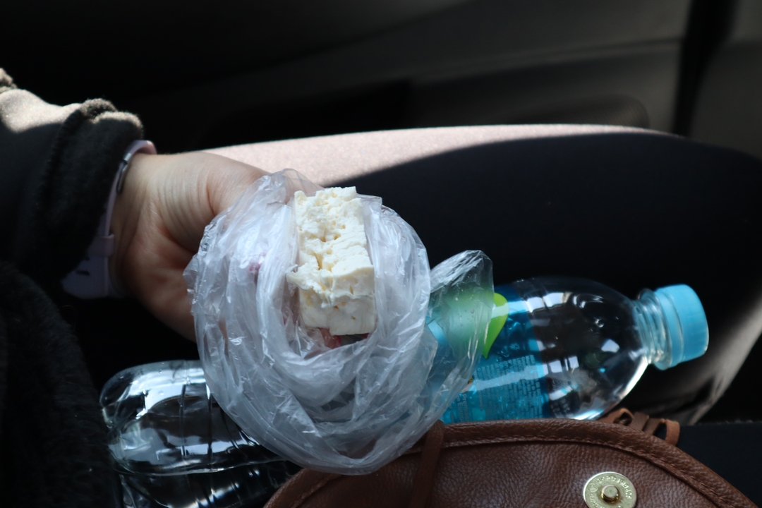 Personne tenant un morceau de fromage emballé dans un sac en plastique.