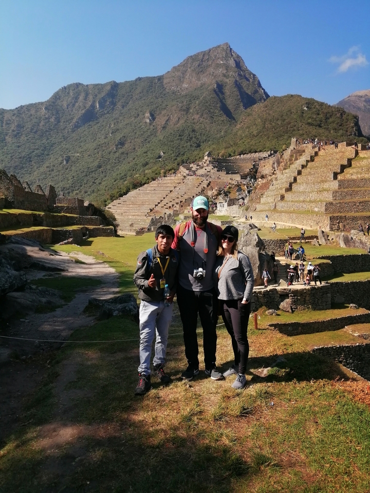 Des visiteurs debout sur les terrasses du Machu Picchu.