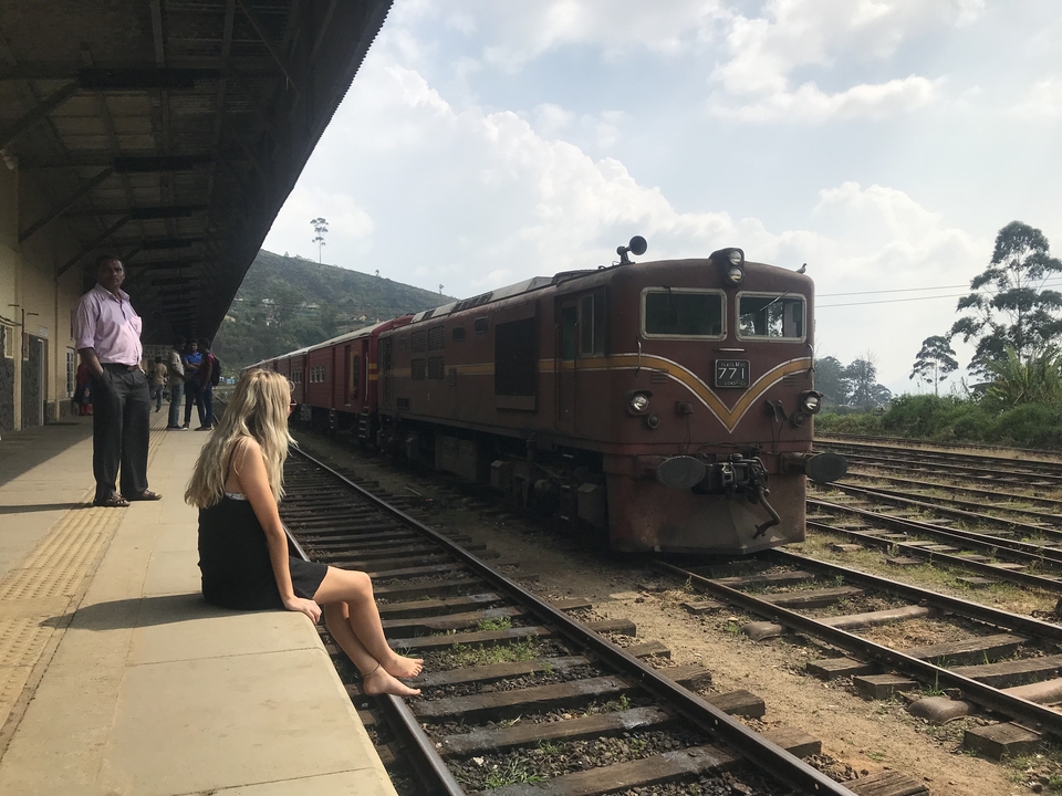 Woman with camera taking a selfie leaning out of a train.