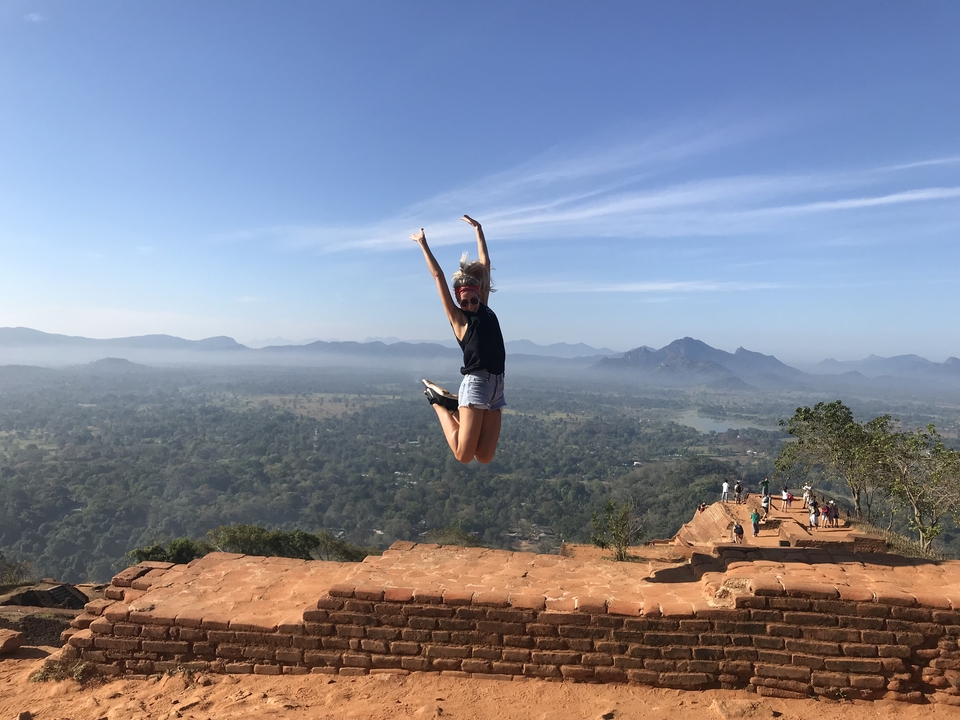 Woman sitting by train tracks, train approaching from a distance.