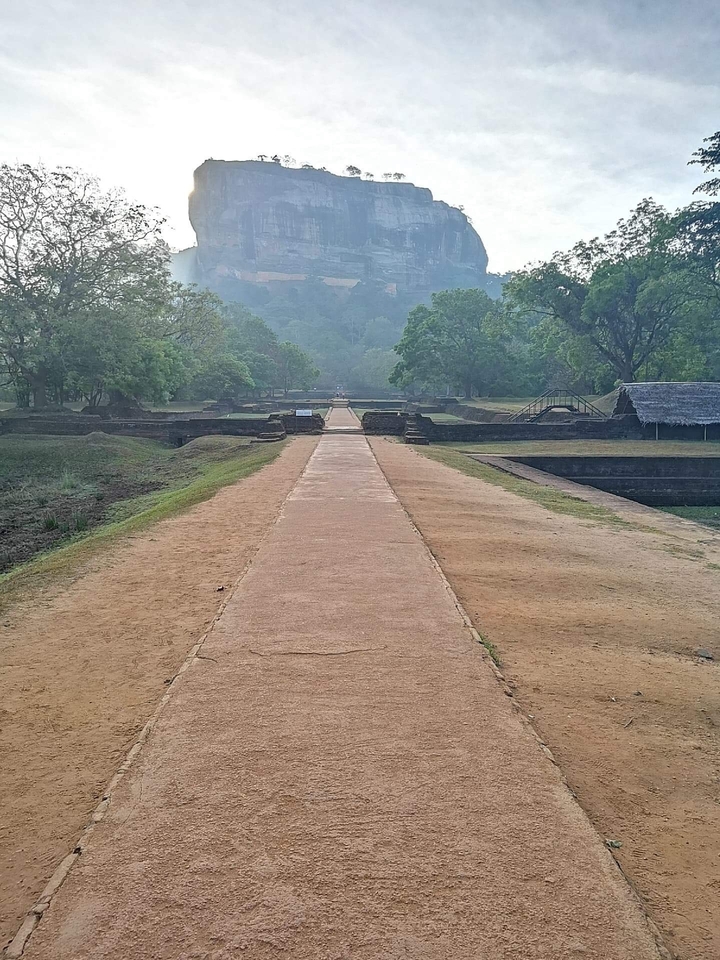 Ancient ruins leading to a forested hill.