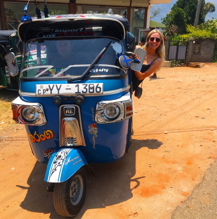 Woman stepping out of a colorful tuk-tuk.