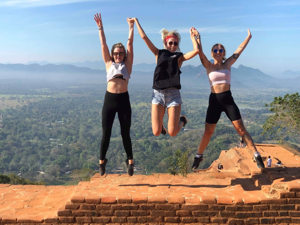 Three women jumping joyfully on a mountain summit.