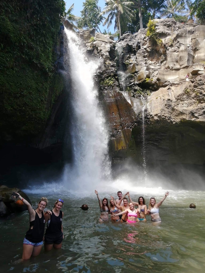 Person standing under a large waterfall.