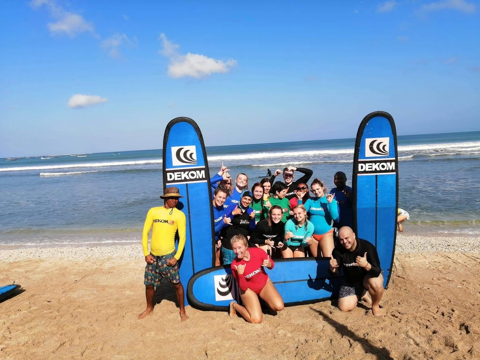Large group of people with surfboards on a beach.