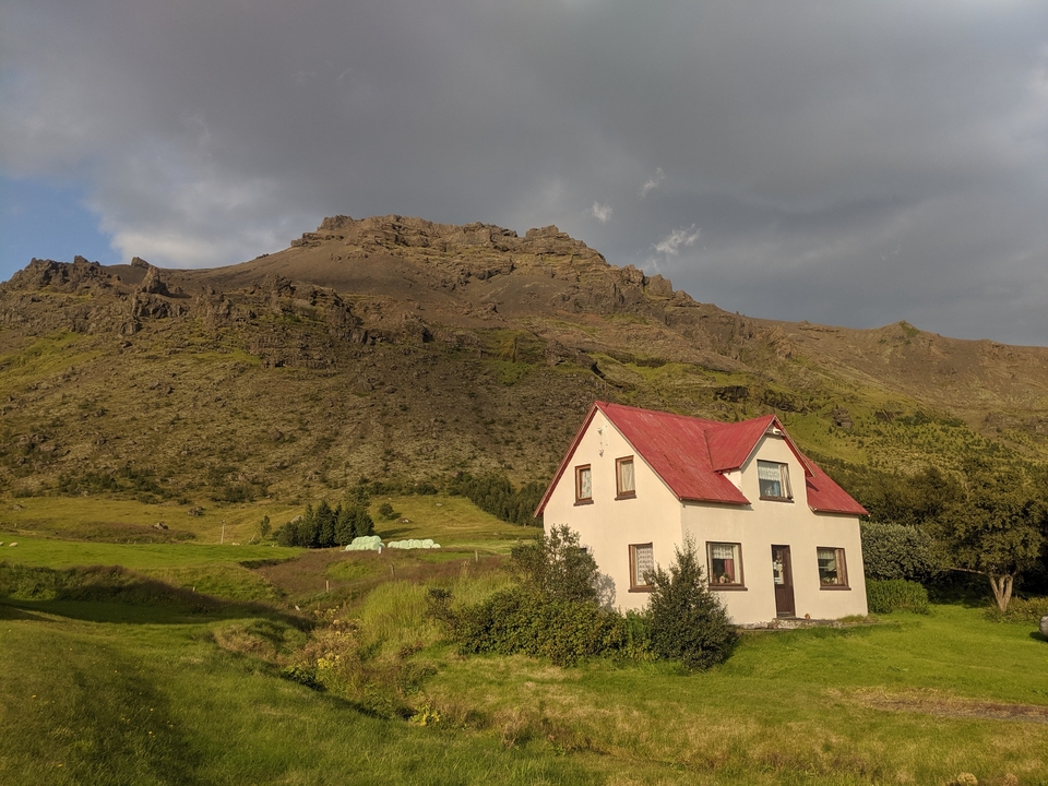 House with red roof situated in front of a mountain.
