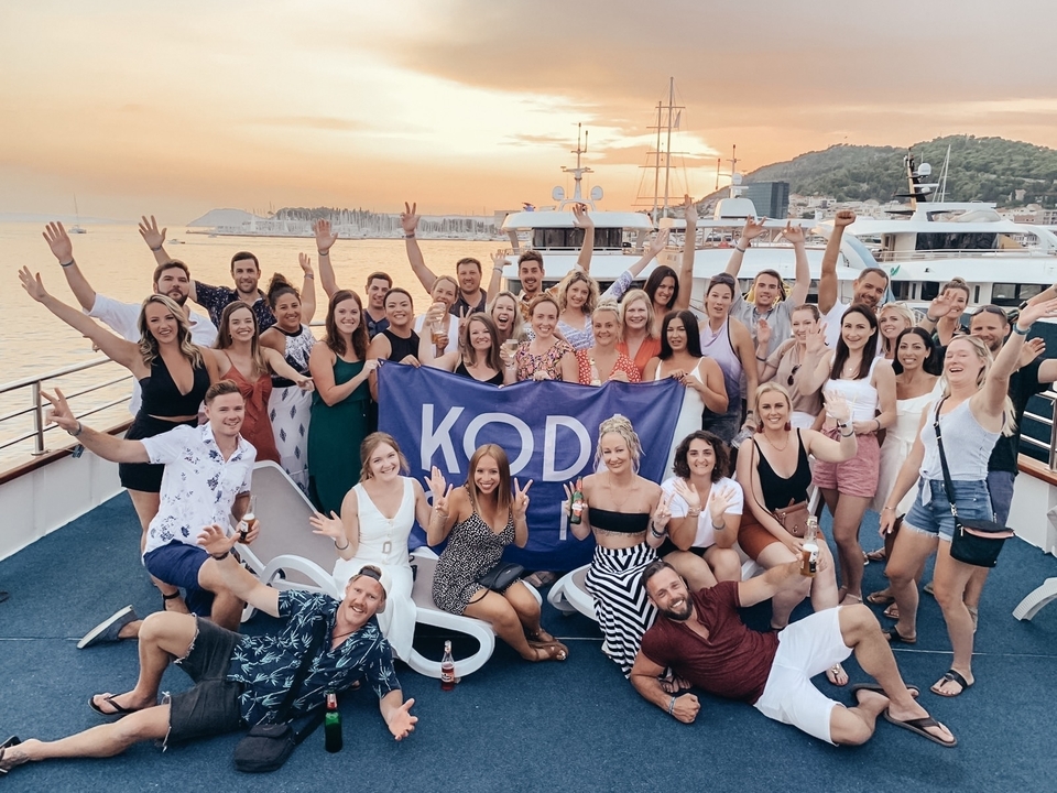 Grand groupe en train de célébrer sur un bateau au coucher du soleil.
