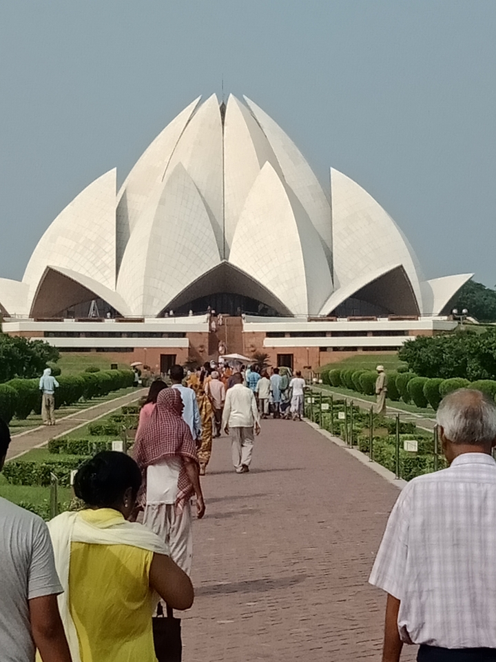 Templo del Loto en Nueva Delhi con visitantes en primer plano.